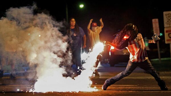 This August 13, 2014, photo by St. Louis Post Dispatch photographer Robert Cohen shows Edward Crawford returning a tear gas canister fired by police who were trying to disperse protesters in Ferguson, Missouri - Sputnik International