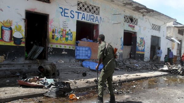 Soldiers inspect the scene of a suicide bomb attack targeting a lunch time crowd at a restaurant in Somalia's capital Mogadishu April 21, 2015 - Sputnik International