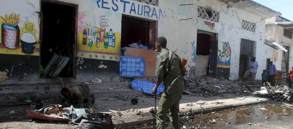 Soldiers inspect the scene of a suicide bomb attack targeting a lunch time crowd at a restaurant in Somalia's capital Mogadishu April 21, 2015 - Sputnik International