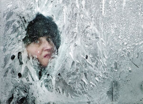 A woman looks out of a window covered in frost on a bus in Bucharest, Romania, in February 2012 - Sputnik International