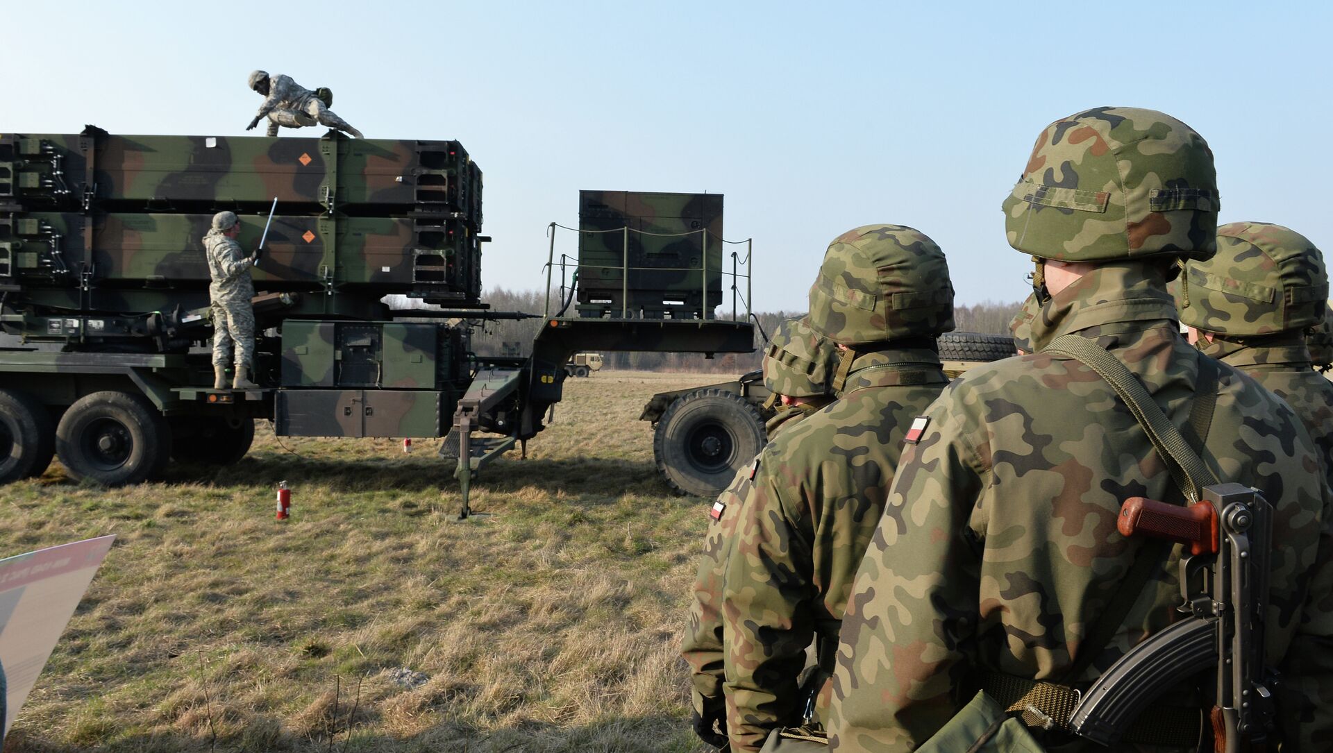 Polish soldiers watch as US troops from the 5th Battalion of the 7th Air Defense Regiment emplace a launching station of the Patriot air and missile defence system at a test range in Sochaczew, Poland, on March 21, 2015. - Sputnik International, 1920, 08.07.2021