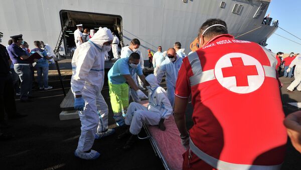Rescuers take care of an immigrant, part of a group of more than 1,370 people, after he disembarked from the Italian military ship San Giusto on August 25, 2014 in the port of Crotone, southern Italy, following the Mare Nostrum rescue operations at sea - Sputnik International