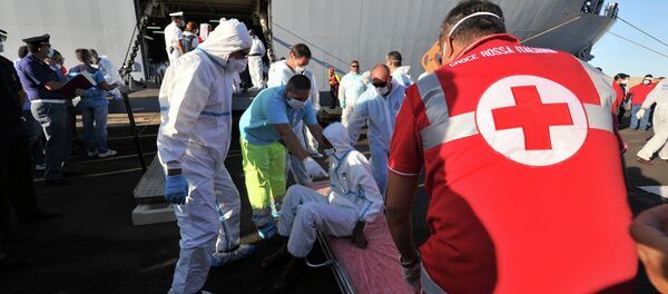 Rescuers take care of an immigrant, part of a group of more than 1,370 people, after he disembarked from the Italian military ship San Giusto on August 25, 2014 in the port of Crotone, southern Italy, following the Mare Nostrum rescue operations at sea - Sputnik International