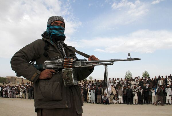 A member of the Taliban insurgent and other people stand at the site during the execution of three men in Ghazni Province on April 18, 2015. A member of the Taliban insurgent and other people stand at the site during the execution of three men in Ghazni Province on April 18, 2015. - Sputnik International