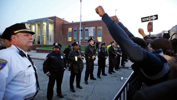 Marchers raise their fists in front of Baltimore police guarding the department's Western District police station during a march for Freddie Gray, Wednesday, April 22, 2015, in Baltimore - Sputnik International