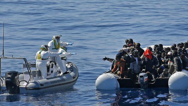 Migrants crowd and inflatable dinghy as rescue vassel  Denaro  (not in picture) of the Italian Coast Guard approaches them, off the Libyan coast, in the Mediterranean Sea - Sputnik International