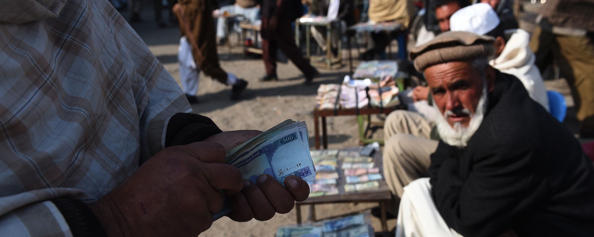 In this photograph taken on December 29, 2014, an Afghan customer (L) counts his Afghani currency notes at a currency exchange market along the roadside in Kabul - Sputnik International, 1920
