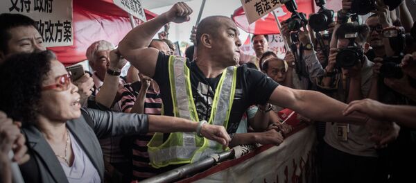 A pro-Beijing protester tries to punch a pro-democracy demonstrator after a heated argument outside the government building in Hong Kong on April 22, 2015. A pro-Beijing protester tries to punch a pro-democracy demonstrator after a heated argument outside the government building in Hong Kong on April 22, 2015. - Sputnik International