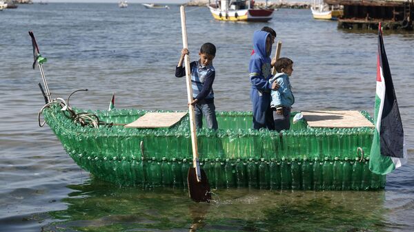 Palestinian children pose for a picture on a makeshift boat made of plastic bottles on April 18, 2015 at the port of Gaza City. - Sputnik International