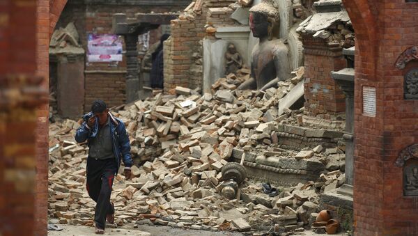 A man cries as he walks on the street while passing through a damaged statue of Lord Buddha a day after an earthquake in Bhaktapur, Nepal - Sputnik International