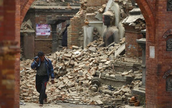 A man cries as he walks on the street while passing through a damaged statue of Lord Buddha a day after an earthquake in Bhaktapur, Nepal - Sputnik International