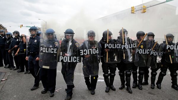 Police advance toward protestors as a store burns, Monday, April 27, 2015, during unrest following the funeral of Freddie Gray in Baltimore. - Sputnik International