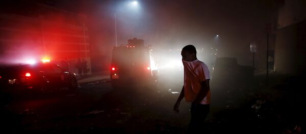 A protester walks through the smoke of burning Baltimore buildings set ablaze by rioters as a police armored car drives past during clashes in Baltimore, Maryland April 27, 2015. Maryland Governor Larry Hogan declared a state of emergency and activated the National Guard to address the violence in Baltimore, his office said on Monday. A protester walks through the smoke of burning Baltimore buildings set ablaze by rioters as a police armored car drives past during clashes in Baltimore, Maryland April 27, 2015. Maryland Governor Larry Hogan declared a state of emergency and activated the National Guard to address the violence in Baltimore, his office said on Monday. - Sputnik International
