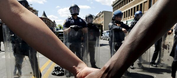 Members of the community hold hands in front of police officers in riot gear outside a recently looted and burned CVS store in Baltimore, Maryland, United States April 28, 2015 - Sputnik International