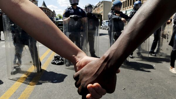 Members of the community hold hands in front of police officers in riot gear outside a recently looted and burned CVS store in Baltimore, Maryland, United States April 28, 2015 - Sputnik International