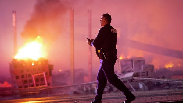 A police officer walks by a blaze, Monday, April 27, 2015, after rioters plunged part of Baltimore into chaos, torching a pharmacy, setting police cars ablaze and throwing bricks at officers - Sputnik International