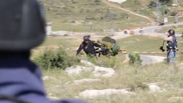 In this video screenshot, an Israeli soldier can be seen pushing a photojournalist. - Sputnik International