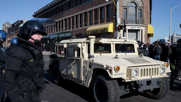 A National Guard vehicle drives by a Maryland State Trooper Tuesday, April 28, 2015, in the aftermath of rioting following Monday's funeral for Freddie Gray. - Sputnik International