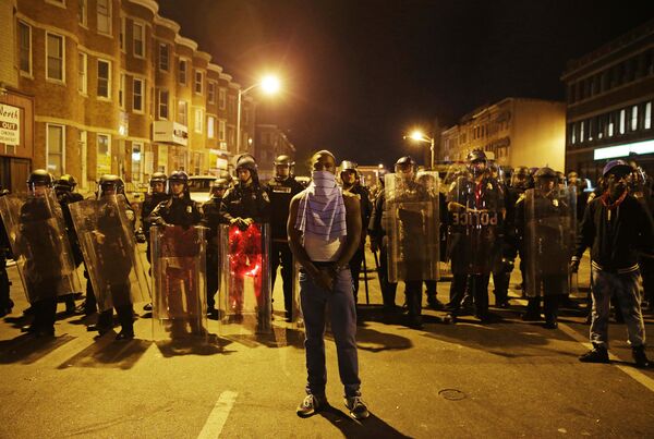 A man stands in front of a line of police officers in riot gear as part of a community effort to disperse the crowd ahead of a 10 p.m. curfew in the wake of Monday's riots following the funeral for Freddie Gray, Tuesday, April 28, 2015, in Baltimore. A man stands in front of a line of police officers in riot gear as part of a community effort to disperse the crowd ahead of a 10 p.m. curfew in the wake of Monday's riots following the funeral for Freddie Gray, Tuesday, April 28, 2015, in Baltimore. - Sputnik International