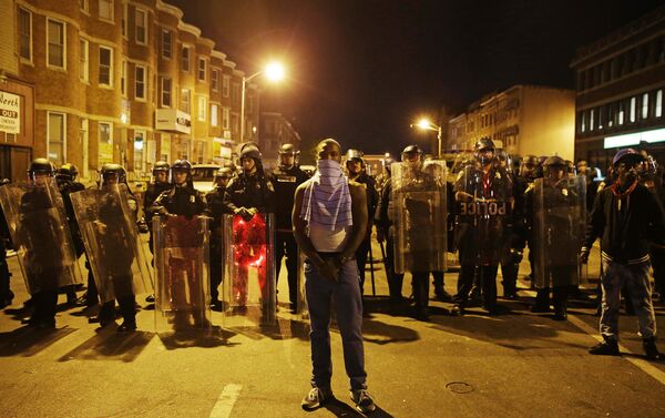 A man stands in front of a line of police officers in riot gear as part of a community effort to disperse the crowd ahead of a 10 p.m. curfew in the wake of Monday's riots following the funeral for Freddie Gray, Tuesday, April 28, 2015, in Baltimore. - Sputnik International