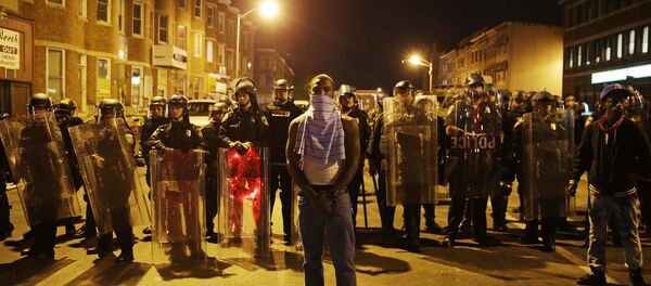 A man stands in front of a line of police officers in riot gear as part of a community effort to disperse the crowd ahead of a 10 p.m. curfew in the wake of Monday's riots following the funeral for Freddie Gray, Tuesday, April 28, 2015, in Baltimore. A man stands in front of a line of police officers in riot gear as part of a community effort to disperse the crowd ahead of a 10 p.m. curfew in the wake of Monday's riots following the funeral for Freddie Gray, Tuesday, April 28, 2015, in Baltimore. - Sputnik International