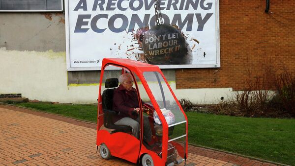 A woman drives a mobility scooter past a Conservative Party billboard in Bedworth, central England, April 1, 2015 - Sputnik International