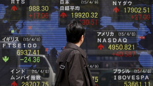 A pedestrian looks at an electronic board showing the stock market indices of various countries outside a brokerage in Tokyo April 9, 2015 - Sputnik International
