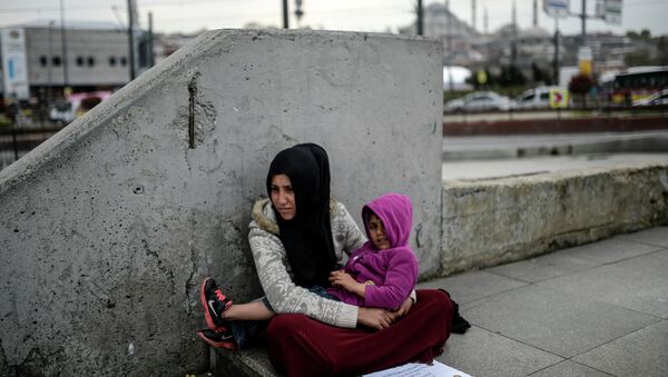 Syrian refugee woman begs as she sits with a child at Eminonu in Istanbul on April 14, 2015 - Sputnik International