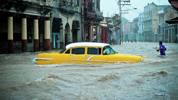 People and vehicles wade through a flooded street during an intense rainstorm in Havana, on April 29, 2015 - Sputnik International