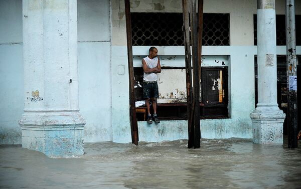 A pedestrian stands on the edge of a window at a flooded street. - Sputnik International