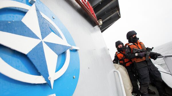 Two Norwegian sailors on board the Norwegian support vessel Valkyrien pose for photographers next to the NATO logo - Sputnik International