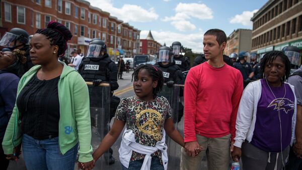 From left, Adrienne Horton, 11 year-old Shenya Milford, Vinny Bevivino, and Lakia McDaniel, all from Baltimore, Md., gather to sing Amazing Grace during a gathering of demonstrators after an evening of riots following the funeral of Freddie Gray on Tuesday, April 28, 2015, in Baltimore - Sputnik International