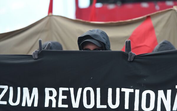 A protester shows the victory sign as he marches with a banner promoting a social revolution worldwide as he takes part in the 'Revolutionary' May Day demonstration in Berlin on May 1, 2015. - Sputnik International