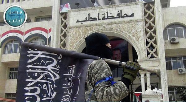 A fighter from Syria's al-Qaeda-linked Nusra Front holds his group flag as he stands in front of the governor building in Idlib province, north Syria. A fighter from Syria's al-Qaeda-linked Nusra Front holds his group flag as he stands in front of the governor building in Idlib province, north Syria. - Sputnik International