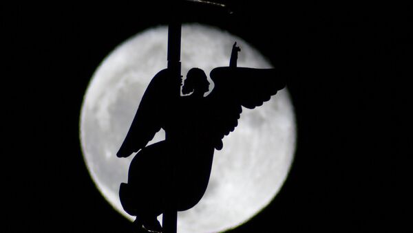 In this photo taken through a telescope lens, the city landmark, a weather vane in the form of an Angel, is fixed atop a spire of the Saints Peter and Paul Cathedral, as it is silhouetted on the rising moon in St.Petersburg, Russia - Sputnik International