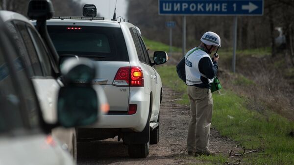 An OSCE observer speaks via radio, in front of the sign saying Shyrokyne, near the village of Shyrokyne, eastern Ukraine - Sputnik International