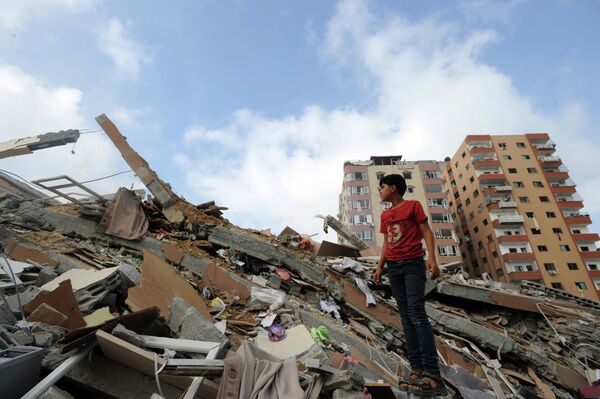 Palestinians collect their belongings from under the rubble of a residential tower, which witnesses said was destroyed by an Israeli air strike in Gaza. Palestinians collect their belongings from under the rubble of a residential tower, which witnesses said was destroyed by an Israeli air strike in Gaza. - Sputnik International