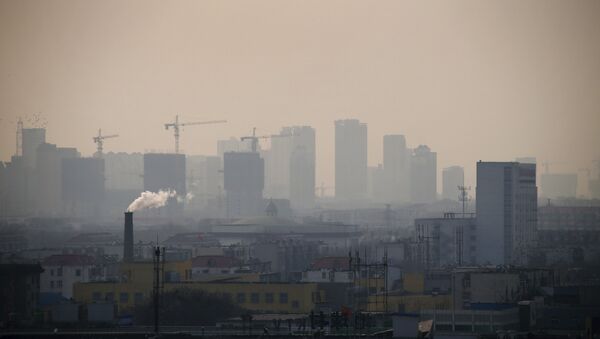 Smoke rises from a chimney among houses as new high-rise residential buildings are seen under construction on a hazy day in the city centre of Tangshan, Hebei province - Sputnik International