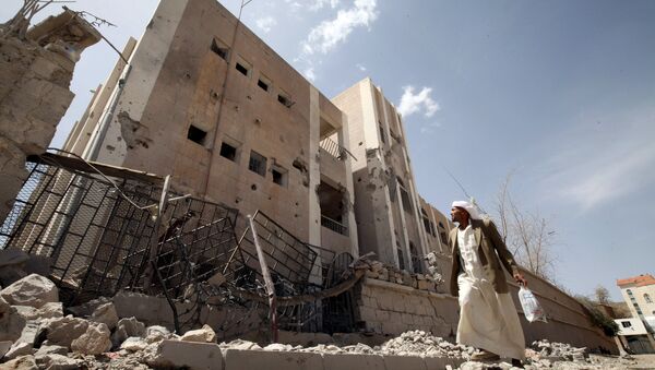 A man looks at a school destroyed by an air strike as he flees his home in Sanaa April 28, 2015 - Sputnik International