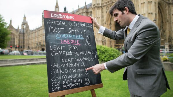 A bookmaker displays the latest odds on the result of the upcoming UK general election outside the Houses of Parliament in central London on May 6, 2015 - Sputnik International