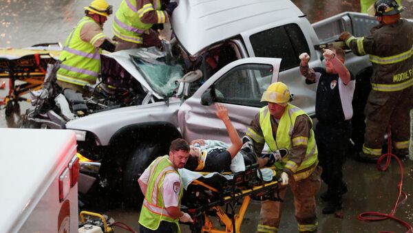 The driver of a truck which crashed during severe weather on Interstate 35 gestures to his rescuers after being cut from the truck in Moore, Okla., Wednesday, May 6, 2015 - Sputnik International