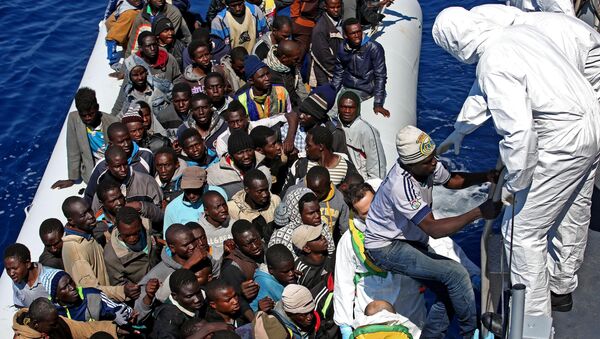 Migrants crowd and inflatable dinghy as rescue vassel  Denaro  of the Italian Coast Guard approaches them, off the Libyan coast, in the Mediterranean Sea, Wednesday, April 22, 2015 - Sputnik International