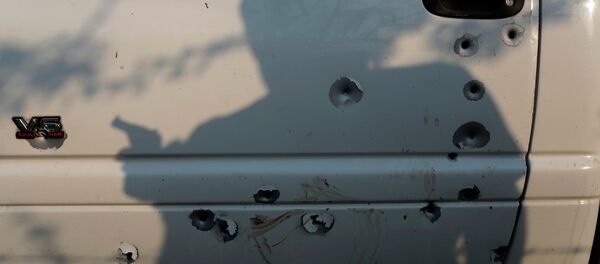 The shadow of a member of the United Front for Security and Development of the State of Guerrero (FUSDEG) vigilante group is seen before a bullet-riddled truck March 31, 2015 at San Juan del Reparo, Guerrero State, Mexico - Sputnik International