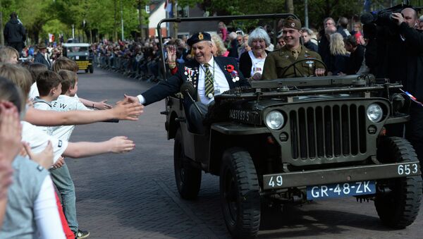 Children reach out to touch the hand of Canadian World War II navy veteran Bert Reynolds, 88, as he takes part in a parade to celebrate the 70th anniversary of the Liberation of the Netherlands in Wageningen, Netherlands on Tuesday, May 5, 2015 - Sputnik International