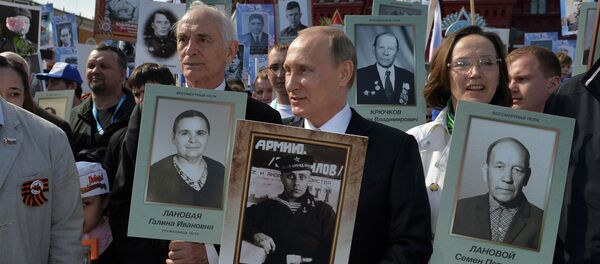 Russian President Vladimir Putin (C) holds a portrait of his father, war veteran Vladimir Spiridonovich Putin as he takes part in the Immortal Regiment march on the Red Square during the Victory Day celebrations in Moscow, Russia, May 9, 2015 - Sputnik International