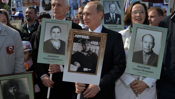 Russian President Vladimir Putin (C) holds a portrait of his father, war veteran Vladimir Spiridonovich Putin as he takes part in the Immortal Regiment march on the Red Square during the Victory Day celebrations in Moscow, Russia, May 9, 2015 - Sputnik International