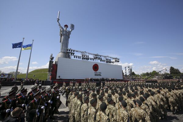 Servicemen marching before the Soviet-era Mother Motherland monument in Kiev, with a Ukrainian and European Union flag fluttering in the background; the monument's head was fitted with a poppy wreath and gold and blue ribbons; May 9, 2015. Servicemen marching before the Soviet-era Mother Motherland monument in Kiev, with a Ukrainian and European Union flag fluttering in the background; the monument's head was fitted with a poppy wreath and gold and blue ribbons; May 9, 2015. - Sputnik International