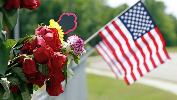 An American flag hangs next to bouquets of flowers on a barbed wire fence Sunday, May 10, 2015, at a makeshift memorial near the site where two Hattiesburg, Miss., police officers were shot to death during a Saturday evening traffic stop - Sputnik International