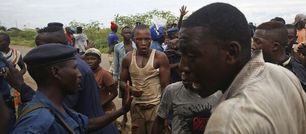 Protesters gesture near female police officer accused of shooting a protestor in Buterere neighbourhood of Bujumbura, Burundi Protesters gesture near female police officer accused of shooting a protestor in Buterere neighbourhood of Bujumbura, Burundi - Sputnik International