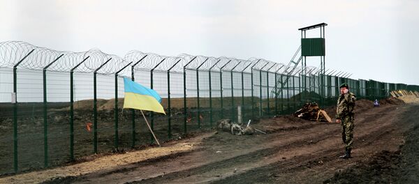 A Ukrainian border guard officer speaks on a phone near a national flag attached to the fence on the Ukrainian-Russian border near Hoptivka, Kharkiv region, eastern Ukraine A Ukrainian border guard officer speaks on a phone near a national flag attached to the fence on the Ukrainian-Russian border near Hoptivka, Kharkiv region, eastern Ukraine - Sputnik International